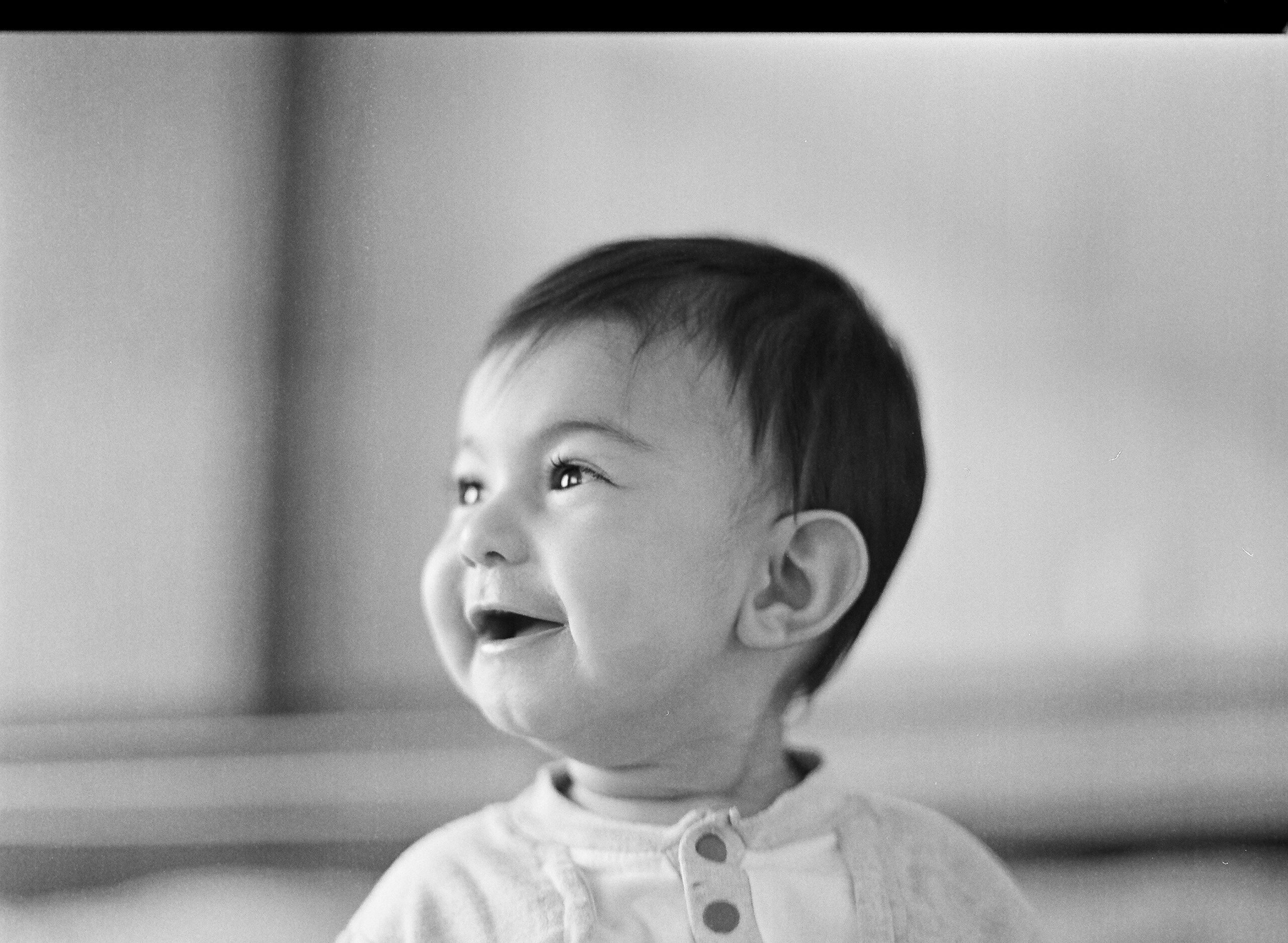 Black and white portrait of a happy newborn baby smiling, capturing precious moments of early parenthood and baby care essentials.
